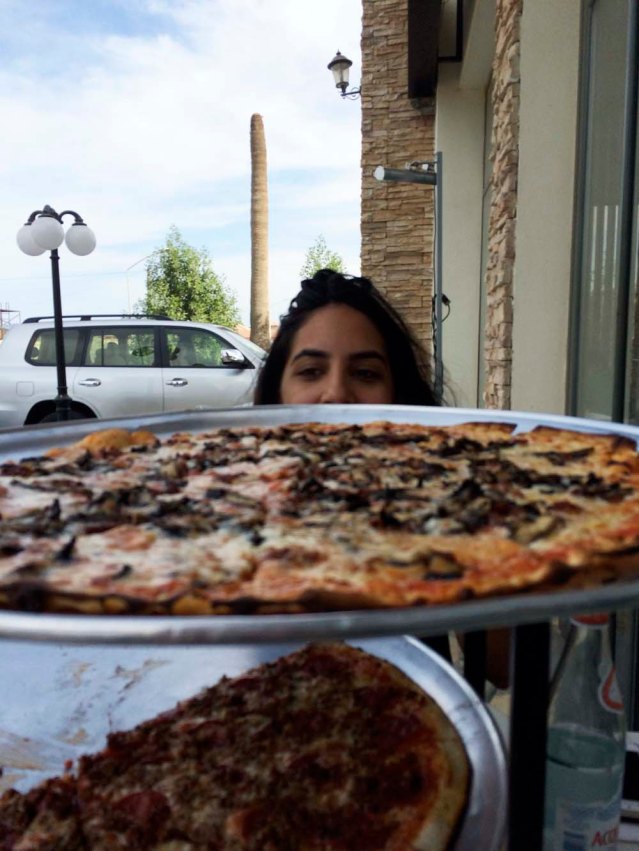 my view at lunch: yasmine, two giant pizzas, and a frondless palm 