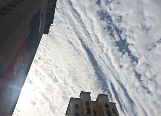 outside gia. a mural by kuwaiti graffiti artist monstariam and one created by god using a mass of condensed vaper floating in an otherwise clear blue sky